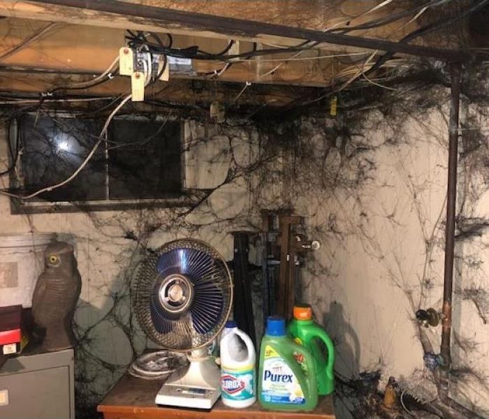Sticky black soot is shown covering walls and items in a basement.